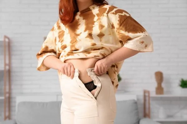 Image of woman trying to do her trousers up after pregnancy weight gain Chorley